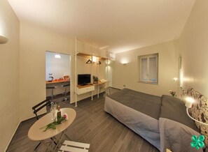 A compact living space with a bed, a dining table with chairs, a kitchenette, and a TV. - Bien-Bì (Naples)