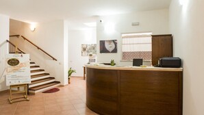 A reception area with a wooden reception desk, a staircase, and a wall-mounted sign. - Albergo Diffuso Il Mandorlo (Baressa)