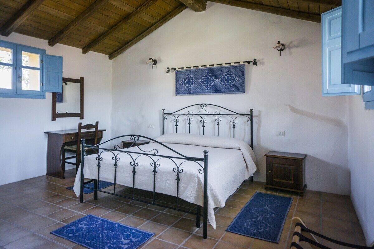 A bedroom with a bed, a desk, a chair, and a small cabinet.