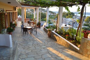 A stone-paved patio with outdoor furniture, potted plants, and a view of the cityscape. - Sofia (Apokoronas)