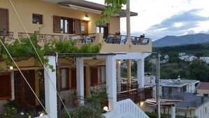 A two-story building with a balcony, potted plants, and outdoor seating. - Sofia (Apokoronas)