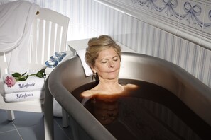 Una bañera con una toalla y una rosa a su lado.