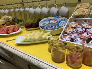 Een ontbijtbuffet met verschillende soorten fruit, yoghurt en gebak.
