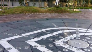 A circular plaza with a geometric pattern and a central reflective sculpture.