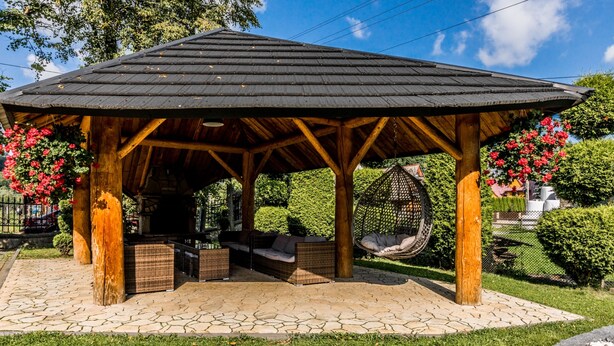 A wooden gazebo with a tiled floor, wicker furniture, and hanging chairs. - Tatrzański Dworek (Bialy Dunajec)