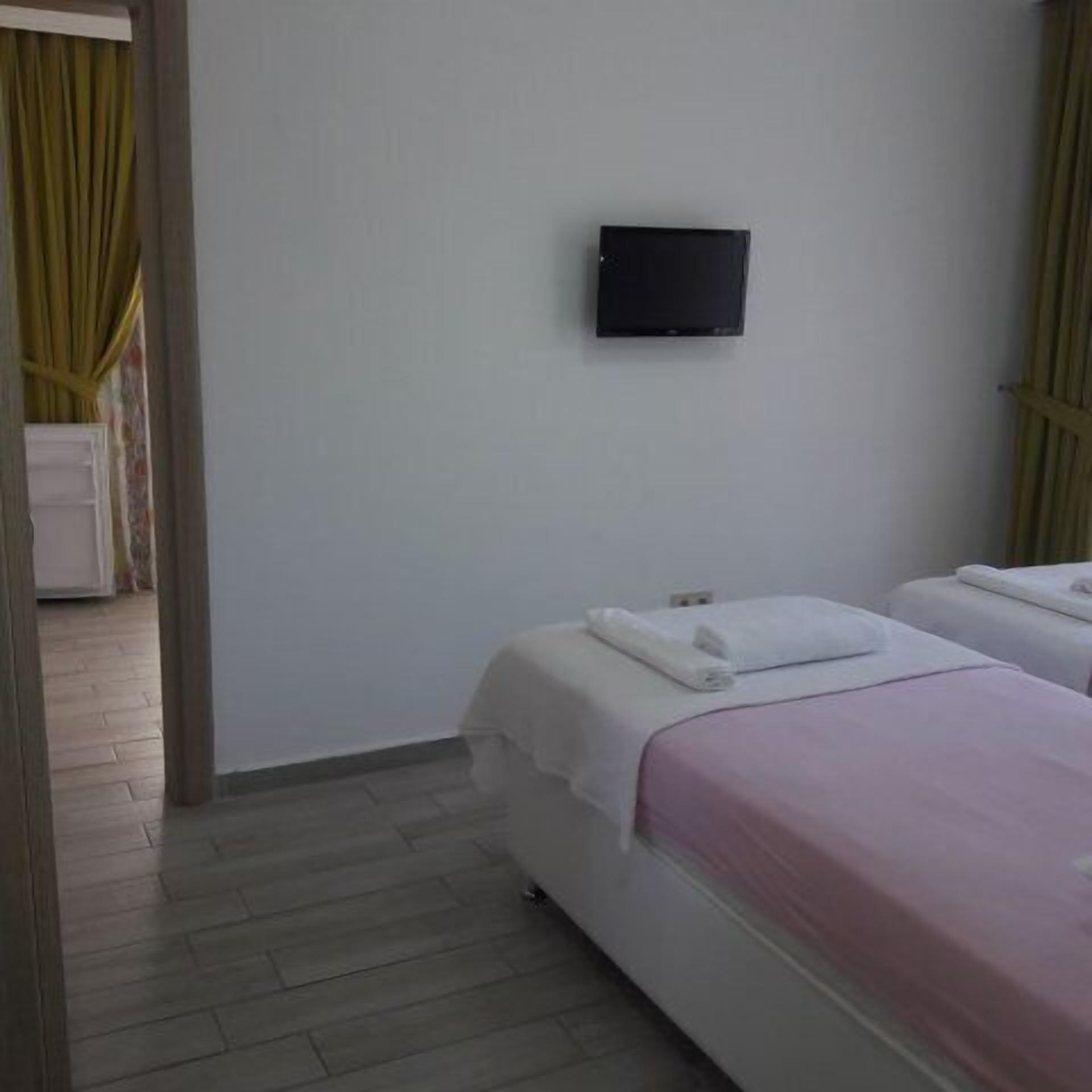A hotel room with two beds, a flat-screen TV mounted on the wall, and a wooden floor.