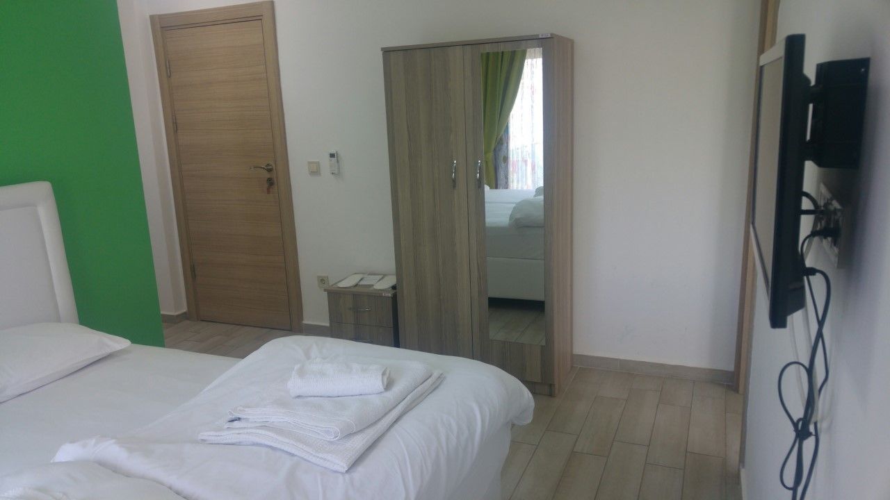 Habitación de hotel con cama, armario, espejo y televisor.