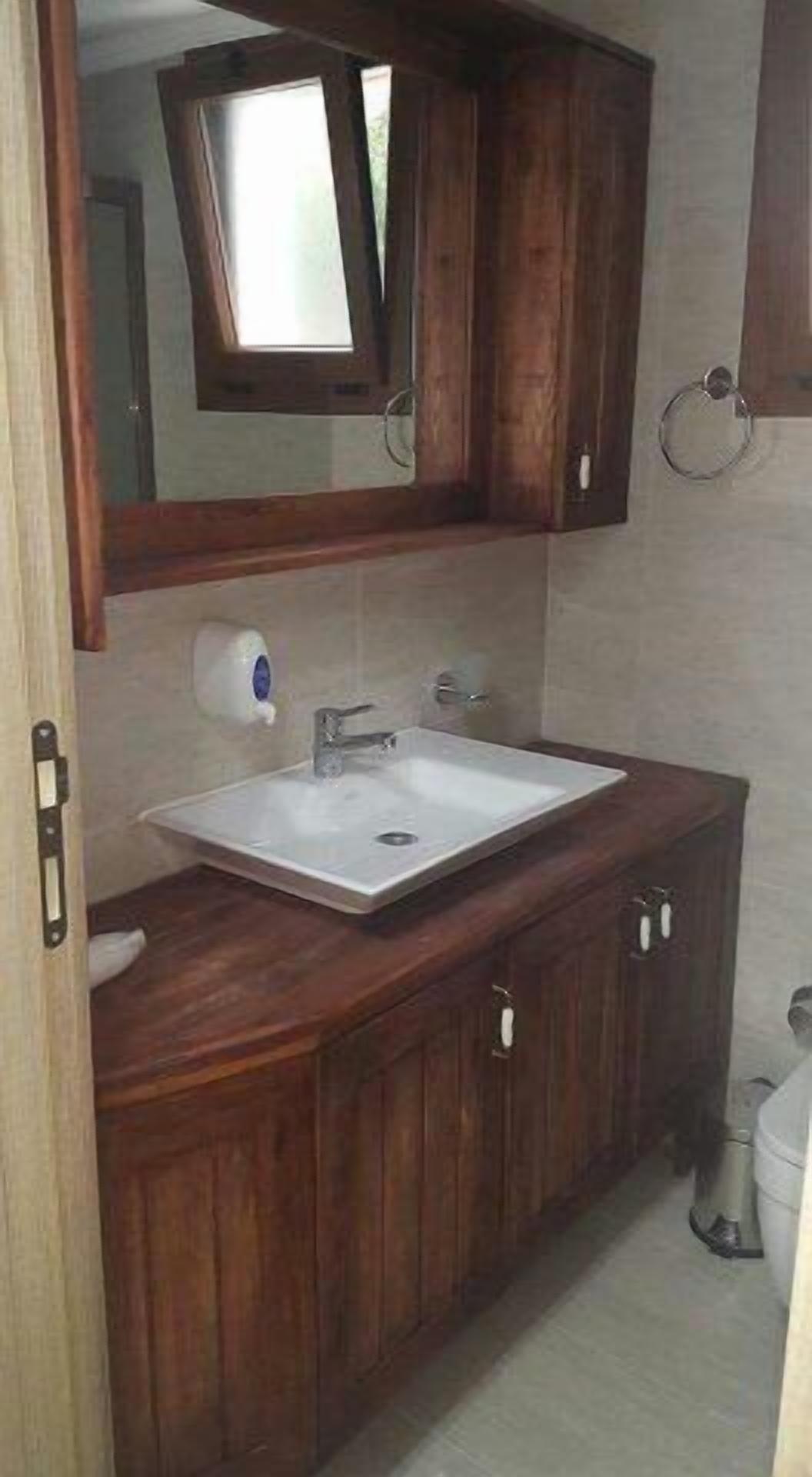Ein Badezimmer mit einem Holzkonsolenunterschrank, einem weißen Waschbecken und einem Spiegel darüber.