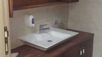 Ein Badezimmer mit einem Holzkonsolenunterschrank, einem weißen Waschbecken und einem Spiegel darüber.