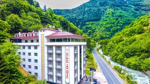 A hotel with a red roof and white walls, surrounded by lush greenery and a river. - Golden Inn Hotel Uzungol (Çaykara)