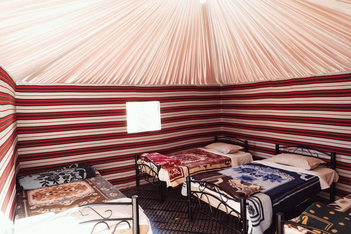 A tent-like room with striped walls, two beds, and a small window.