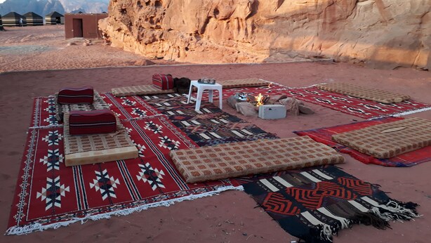 A desert campsite with tents, a fire pit, and traditional rugs. - Wadi Rum Firecamp (Wadi Rum)