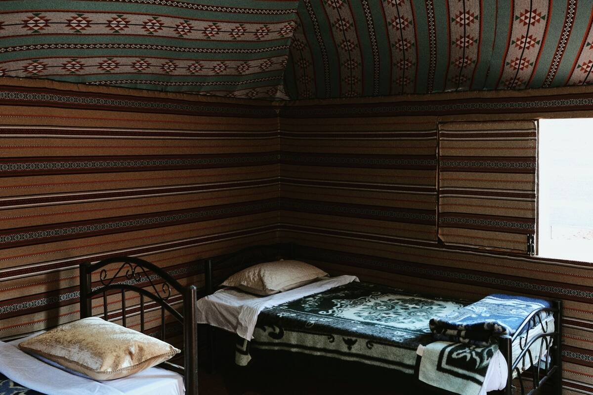 A room with two beds, a window, and a patterned ceiling.