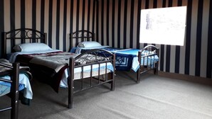 A room with three metal bunk beds arranged in a row, a striped wall, and a window with a view. - Wadi Rum Firecamp (Wadi Rum)