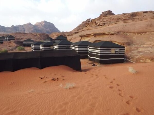 A desert landscape with several black and white striped tents.