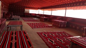 A room with a patterned ceiling, multiple seating areas, and large windows. - Wadi Rum Firecamp (Wadi Rum)