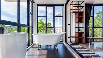 Un baño moderno con una bañera independiente, ventanas amplias y vistas a la vegetación.