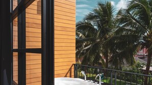 A modern outdoor bathtub on a wooden deck with a view of palm trees and a clear sky. - Book a Bed Poshtel - Hostel (Phuket)