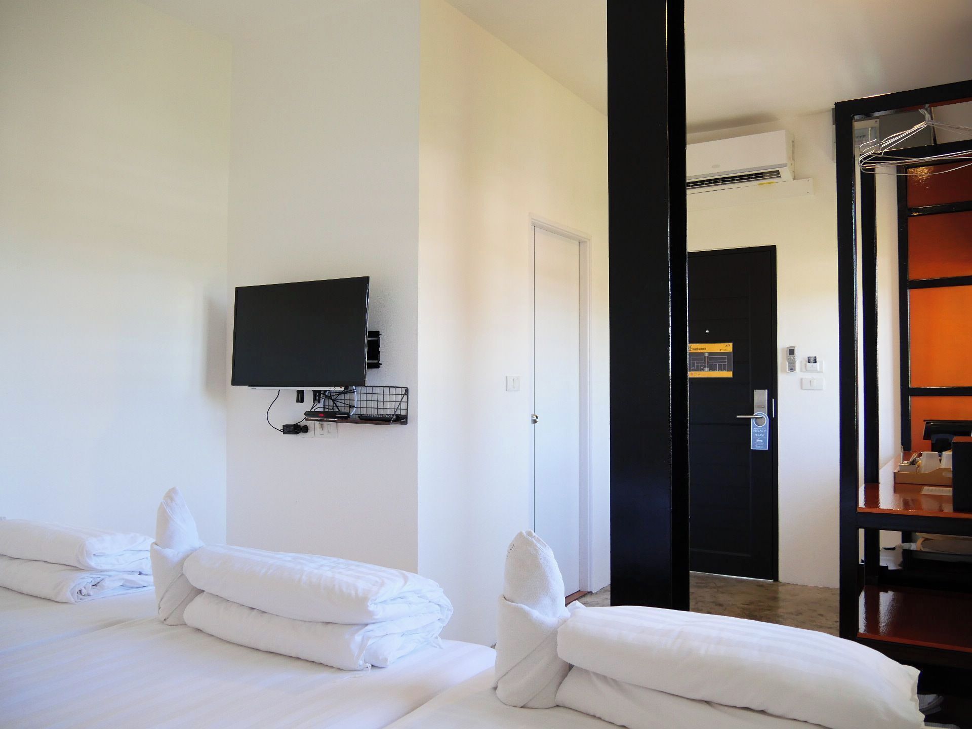 A hotel room with a bed, a TV mounted on the wall, and a door leading to a bathroom.
