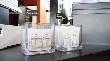 Two glass candle holders with 'The Tint' branding and 'book a bed' text, placed on a dark surface with a white device in the background.