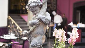Una estatua de un niño sosteniendo un pájaro en una habitación con una escalera y paredes rosas.