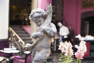 Una estatua de un niño sosteniendo un pájaro en una habitación con una escalera y paredes rosas.