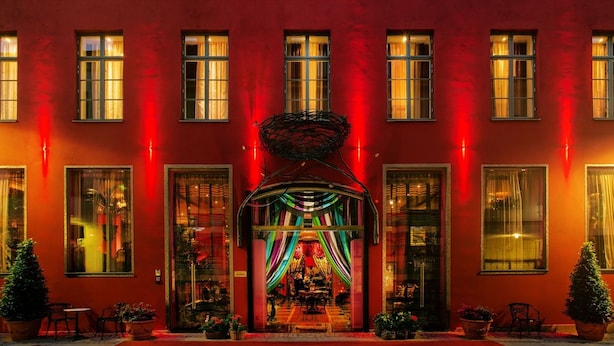 Un edificio rojo con varias ventanas y una entrada central adornada con cortinas coloridas.