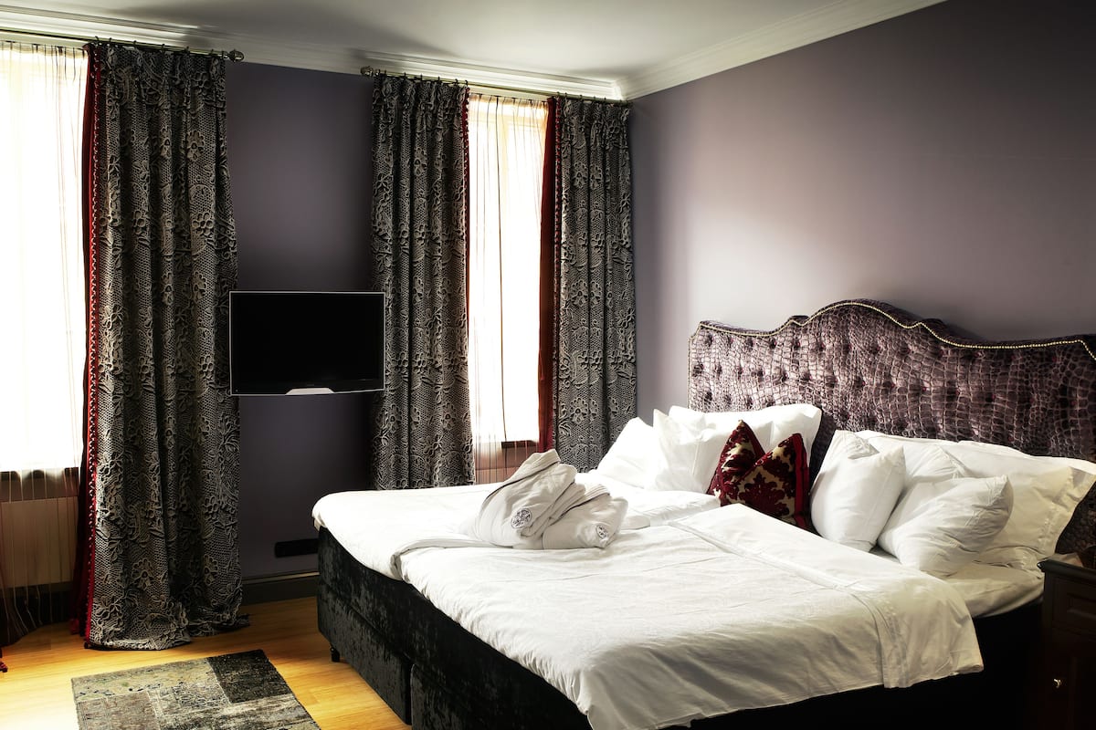 Une chambre d’hôtel avec un grand lit, des rideaux occultants, un téléviseur à écran plat et une tête de lit au motif texturé.