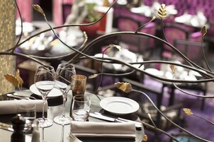 A table set for dining with multiple wine glasses, a small glass container, and a folded napkin.