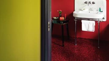 A bathroom with a red floor, a white sink, and a small table with toiletries.