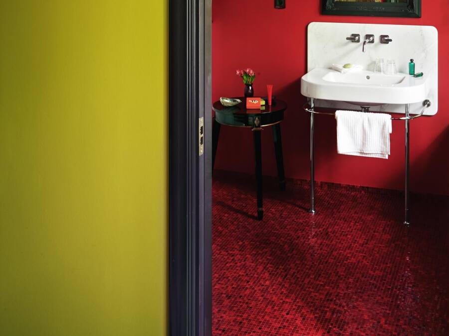 A bathroom with a red floor, a white sink, and a small table with toiletries.