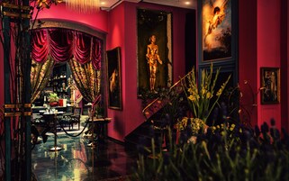 Un interior lujoso con una gran escalera, cortinas elegantes y arte clásico.