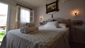 A neatly made bed with rolled towels, a painting on the wall, and two wall-mounted lights. - Cunda Poseidon Hotel (Ayvalik)