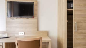 Un bureau en bois avec un téléviseur fixé au-dessus, une chaise et un meuble en bois dont la porte est entrouverte.