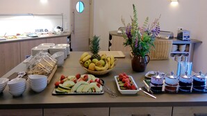 A buffet with various fruits, a toaster, and a vase of flowers. - Hotel zur Ostsee (Graal Mueritz)