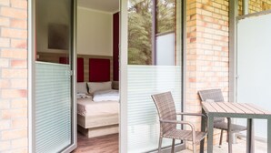 A room with a bed, a sliding glass door leading to an outdoor area with a table and chairs. - Hotel zur Ostsee (Graal Mueritz)
