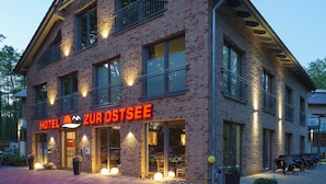 A hotel with a brick facade, large windows, and outdoor seating. - Hotel zur Ostsee (Graal Mueritz)