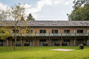 Een gebouw met een bakstenen gevel, meerdere ramen en een overdekt terras.