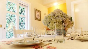 A dining table set with plates, cutlery, and glasses, with a vase of flowers in the center. - Casa Yvitú Blue Bird Hotel (Campos do Jordão)