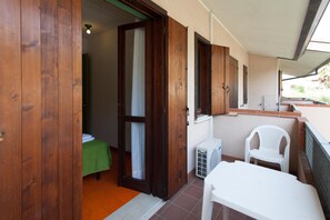 Une pièce de taille modeste, avec une porte en bois, une petite table, une chaise blanche et une nappe verte.