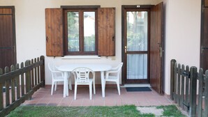 A patio with a white table and chairs, wooden shutters, and a tiled floor. - Villa Valentina (Jesolo)