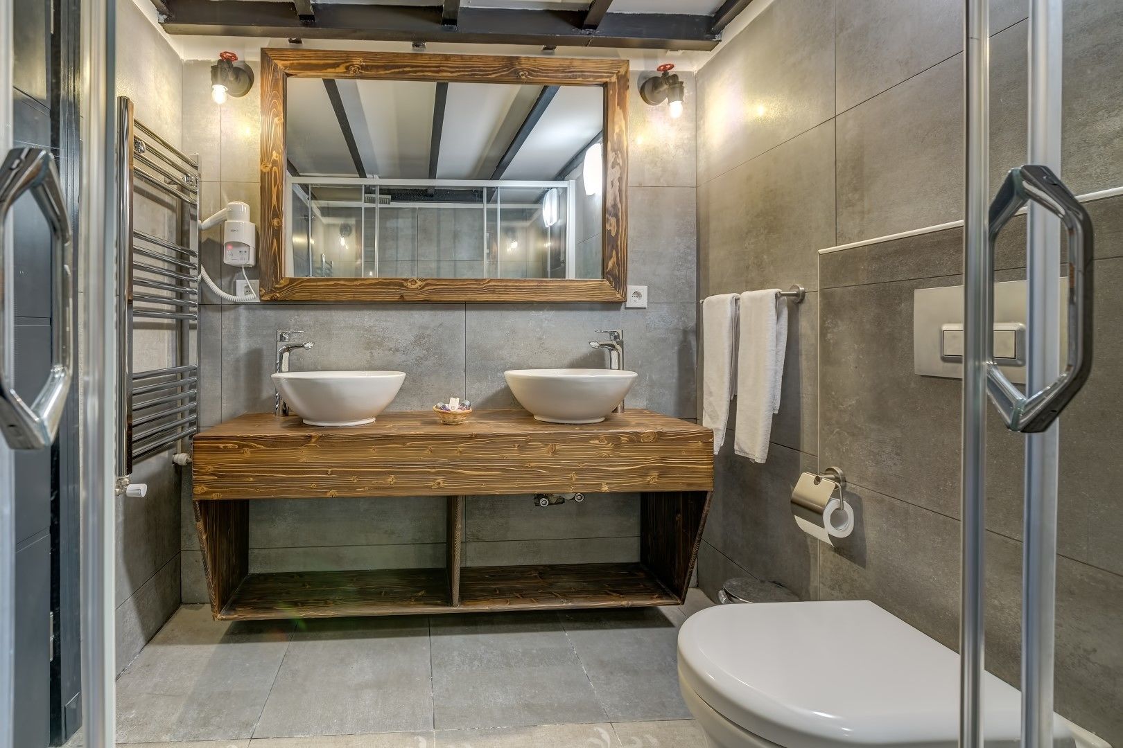 A modern bathroom with two sinks, a large mirror, and a shower.