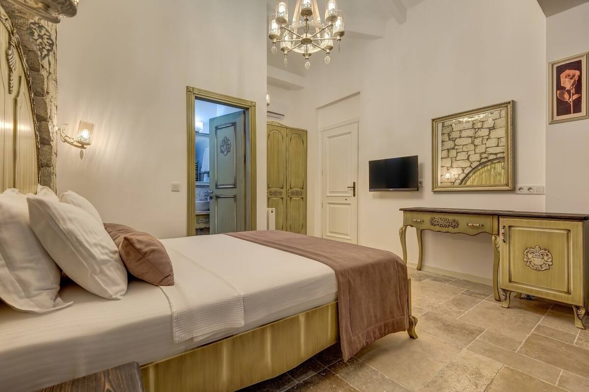 Un dormitorio con cama, cómoda, televisor y espejo.