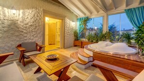 Een gezellige kamer met een stenen muur, een houten tafel, een bank en een jacuzzi.