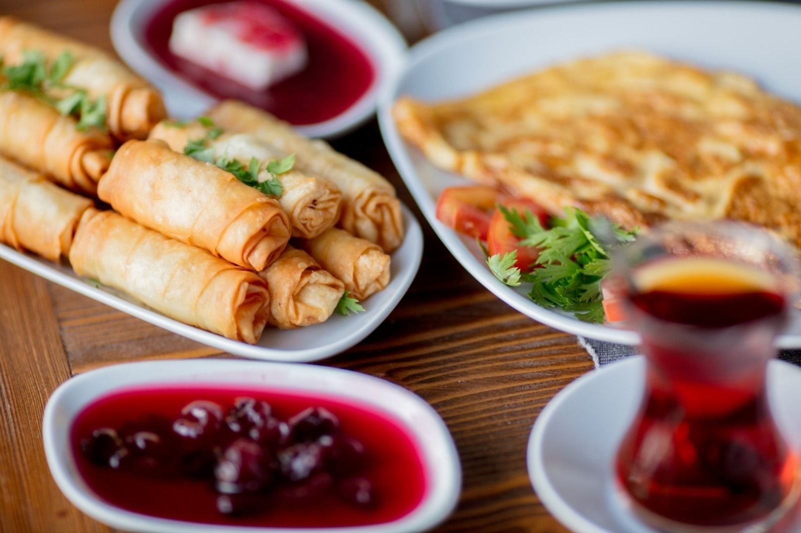 A table with various dishes including spring rolls, a salad, and a bowl of red sauce.