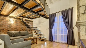 Een moderne woonkamer met een bakstenen muur, een houten trap en een groot raam met gordijnen.