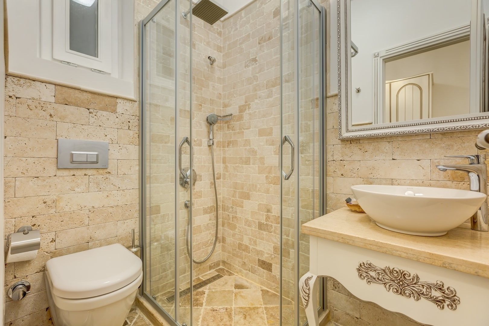 Ein Badezimmer mit einer gläsernen Duschkabine, einem weißen Waschbecken und einer Toilette.