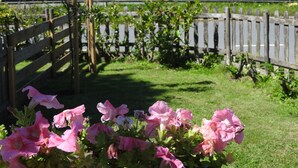 Un jardín con flores rosadas y una valla de madera.