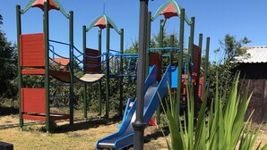 A playground with slides and climbing structures, surrounded by a garden with various flowers. - Black Bull Inn (Immingham)
