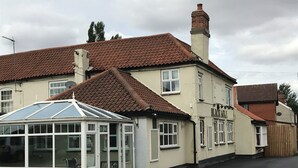 A two-story building with a red-tiled roof, a conservatory with glass doors, and a sign that reads "Mansion Hotel". - Black Bull Inn (Immingham)